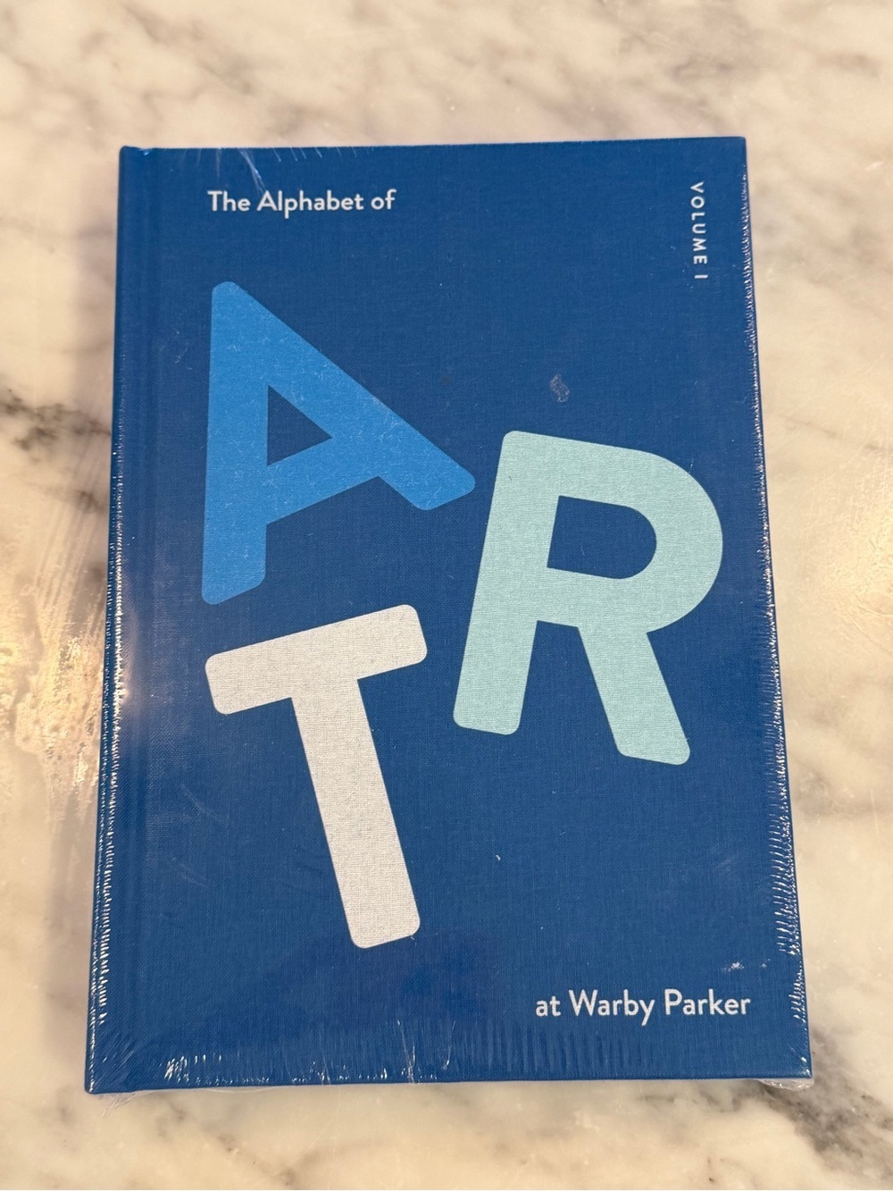 Warby Parker Blue Hardcover Book with Light Blue and White Lettering
